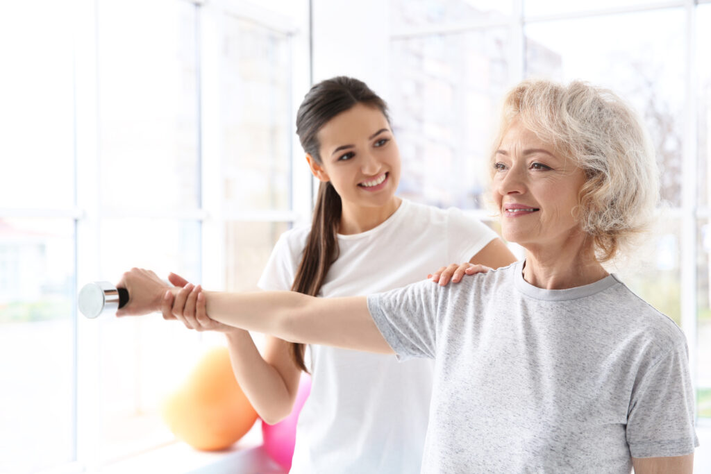 Physiotherapist working with elderly patient in modern clinic